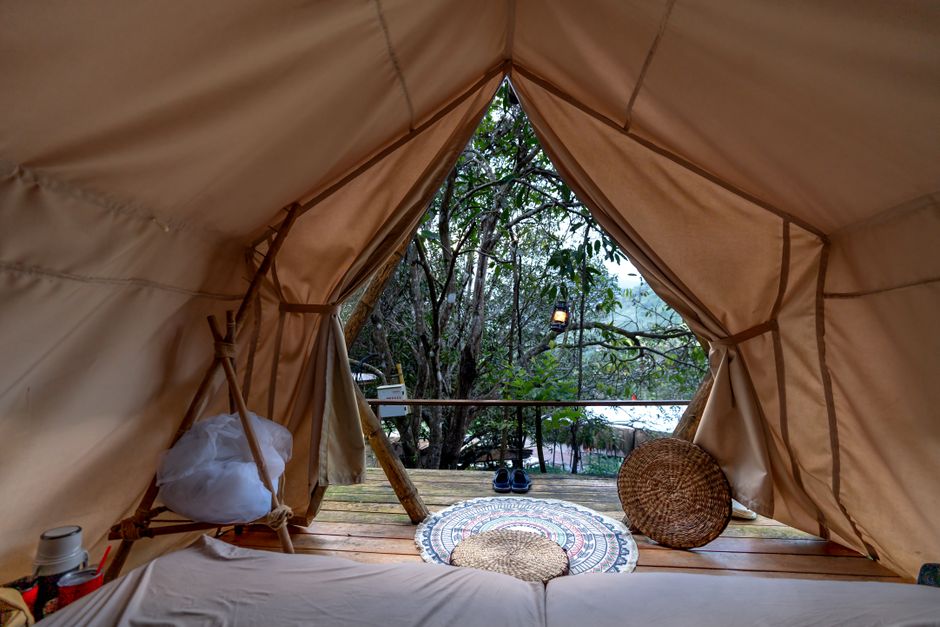 Experience tranquility in a cozy tent overlooking a serene forest setting.