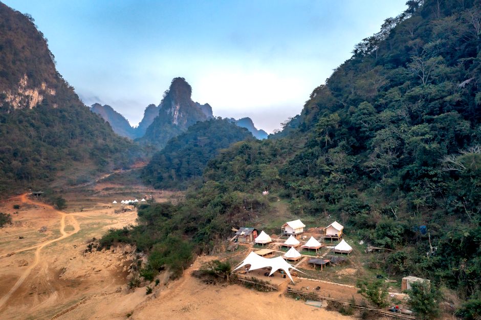 Scenic aerial view of tents nestled in a mountain valley lush with greenery.